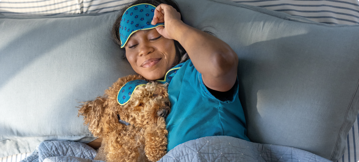 Pes odpočívá s páníčkem v posteli